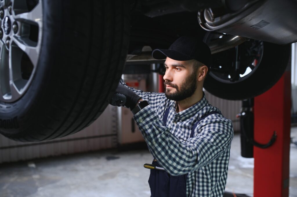Auto mechanic working underneath a lifted car